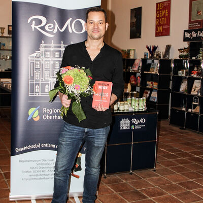 Vincent Kliesch mit dem Buch "Auris" und einem Blumenstrau&szlig; in den  H&auml;nden.