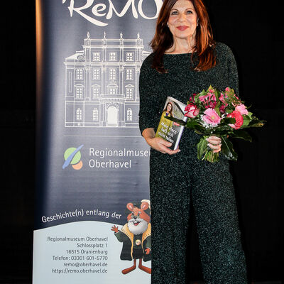 Claudia Wenzel mit ihrem Buch und einem Strau&szlig; Blumen in der Hand