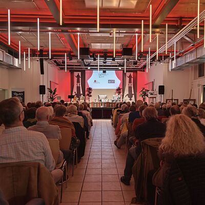 Vollbildaufnahme des Gro&szlig;en Saals in der Kulturfuge Oberhavel: zu sehen ist ein gro&szlig;er Teil des Publikums von Hinten sowie die B&uuml;hne.