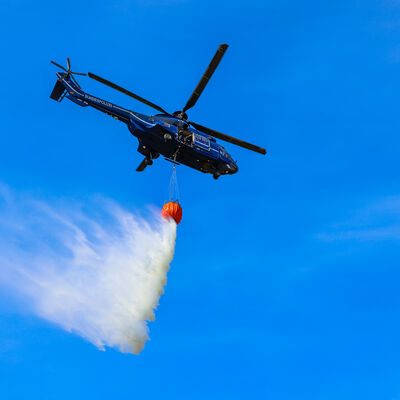 Bildaufnahme vom Boden aus, eines Hubschrauber der Bundespolizei beim Abwurf von Wasser aus einem Au&szlig;enlastbeh&auml;ter "Bambi-Bucket" heraus, &uuml;ber eine angenommenen Brandstelle.