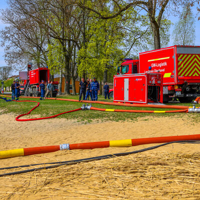 Hochleistungs-Wasserf&ouml;rdersystem
- verlegte F-Schl&auml;uche im Vordergrund
- abgesetztes Pumpenmodul entlang der Schlauchstrecke
- Ger&auml;tewagen Logistik (hinten rechts)
- Wechselladerfahrzeug (hinten links)