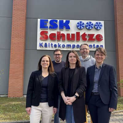 Drei Frauen und zwei M&auml;nner stehen in Zweierreihen vor einem Geb&auml;ude mit dem Schild ESK Schultze K&auml;ltekomponenenten.