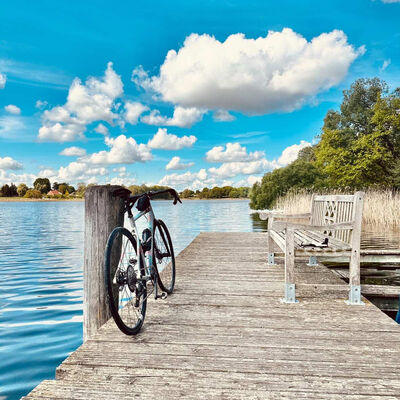 Ein Fahrrad lehnt an einem Pfosten auf einem Steg vor blauem Himmel.