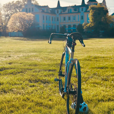 Ein Fahrrad steht vor einem Schloss auf dem Rasen.