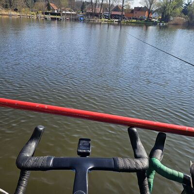 Ein Fahrrad steht auf einem Boot, der Lenker zeigt Richtung Ufer.