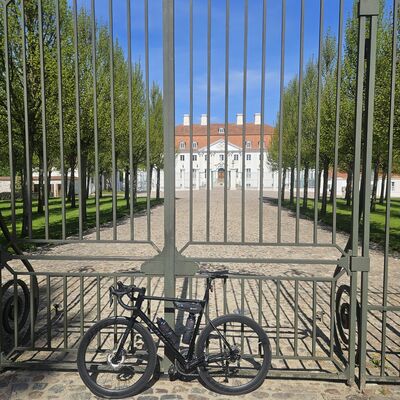 Ein Fahrrad lehnt am Eingangstor zu einem Schloss.