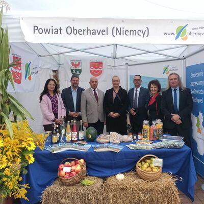 Ein Messestand vom Landkreis Oberhavel. Sieben Personen stehen dahinter und l&auml;cheln in die Kamera.